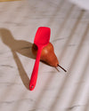 The GIR Red 3 Piece Mini Tool Set Mini Spoonula resting on a pear on a marble surface. 