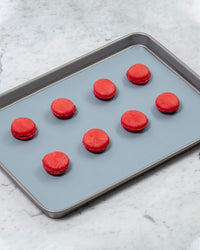 The Slate 12 x 17 Baking mat on a baking tray with red macaroons on it.