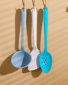A GIR Perforated Spoon, Flip and Ladle hanging on a creamish background. 