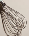 Close up of the Whisk head on a cream background.