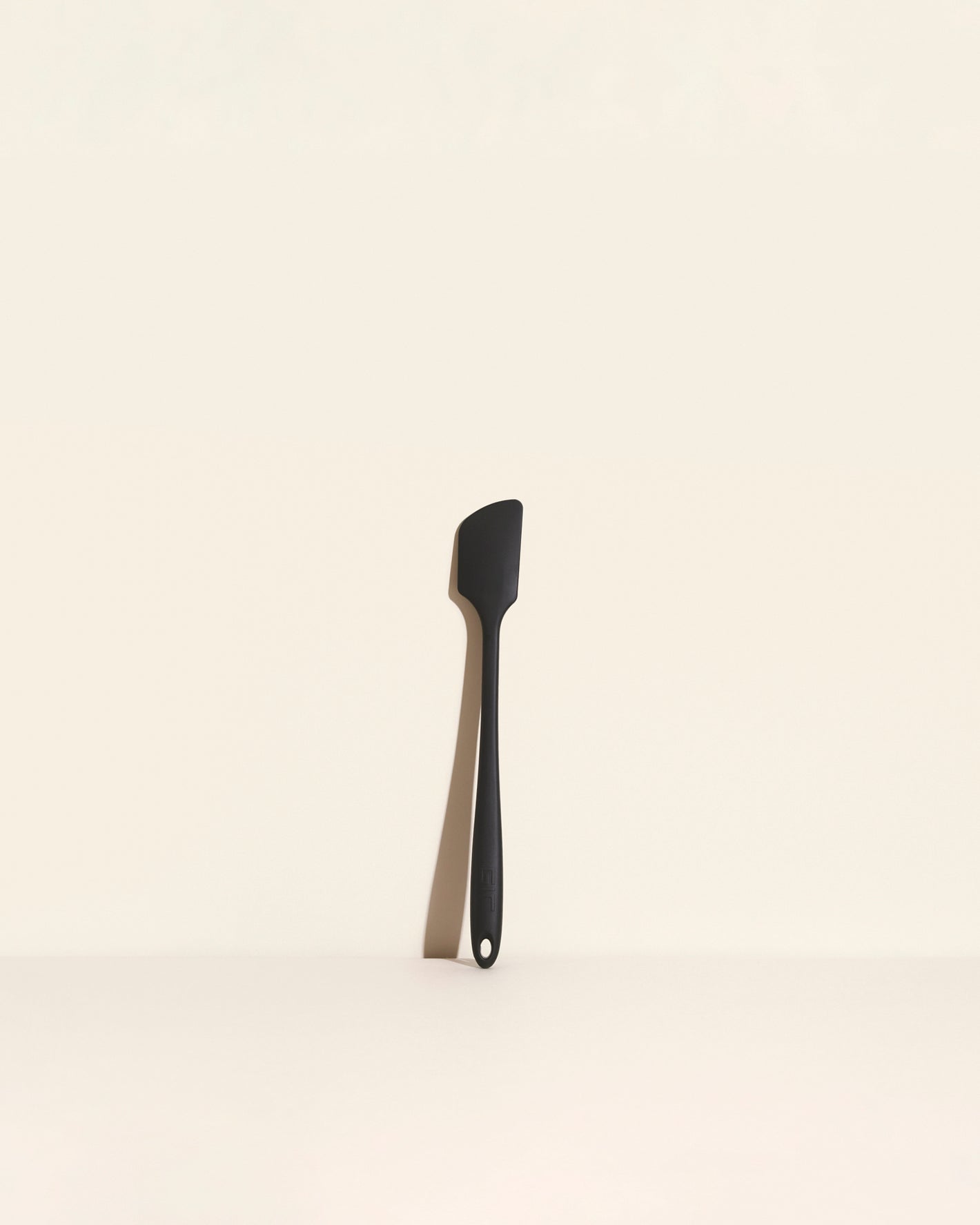 The Black Skinny Spatula on a cream background. 