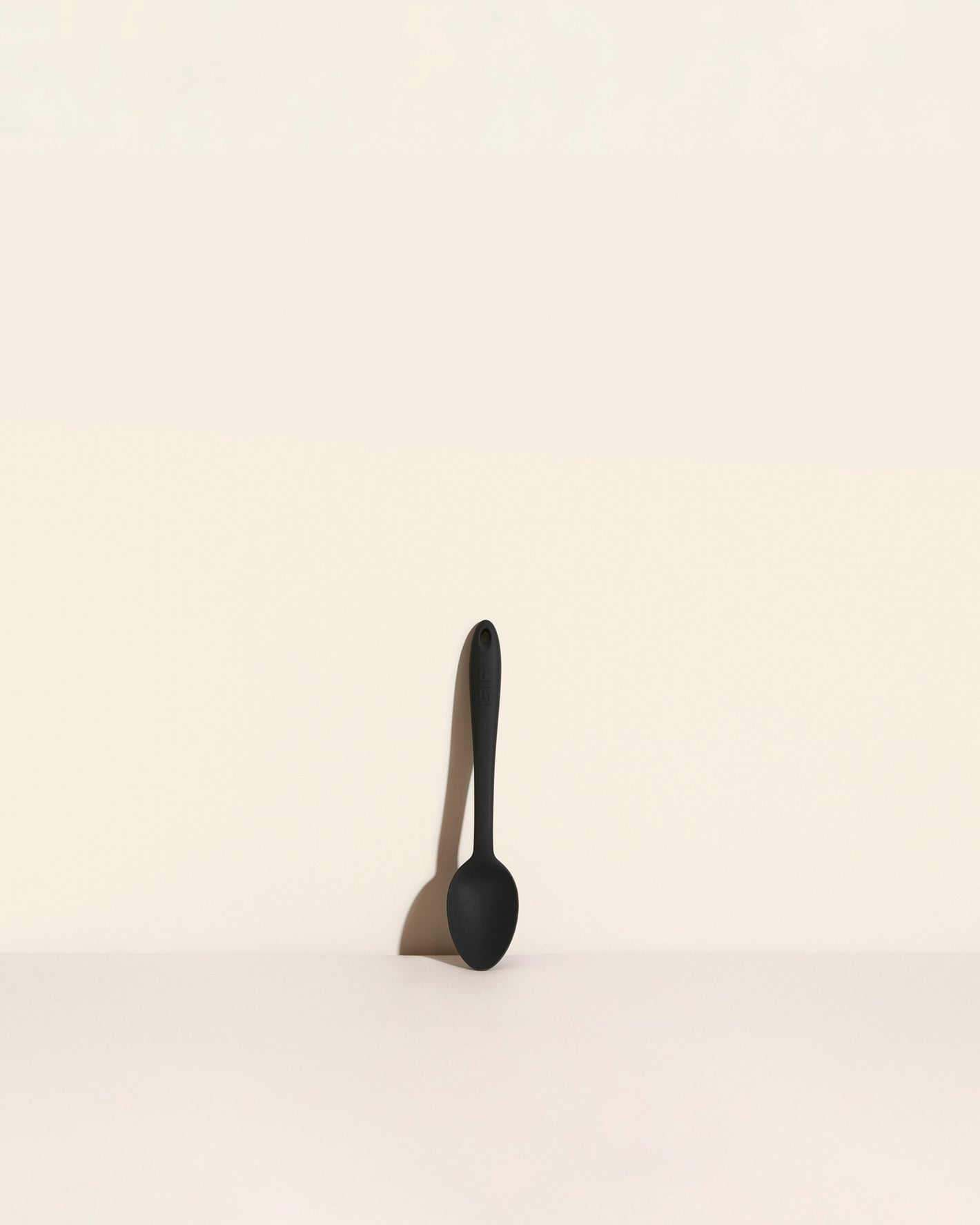 The Black Mini Spoon on a cream background. 