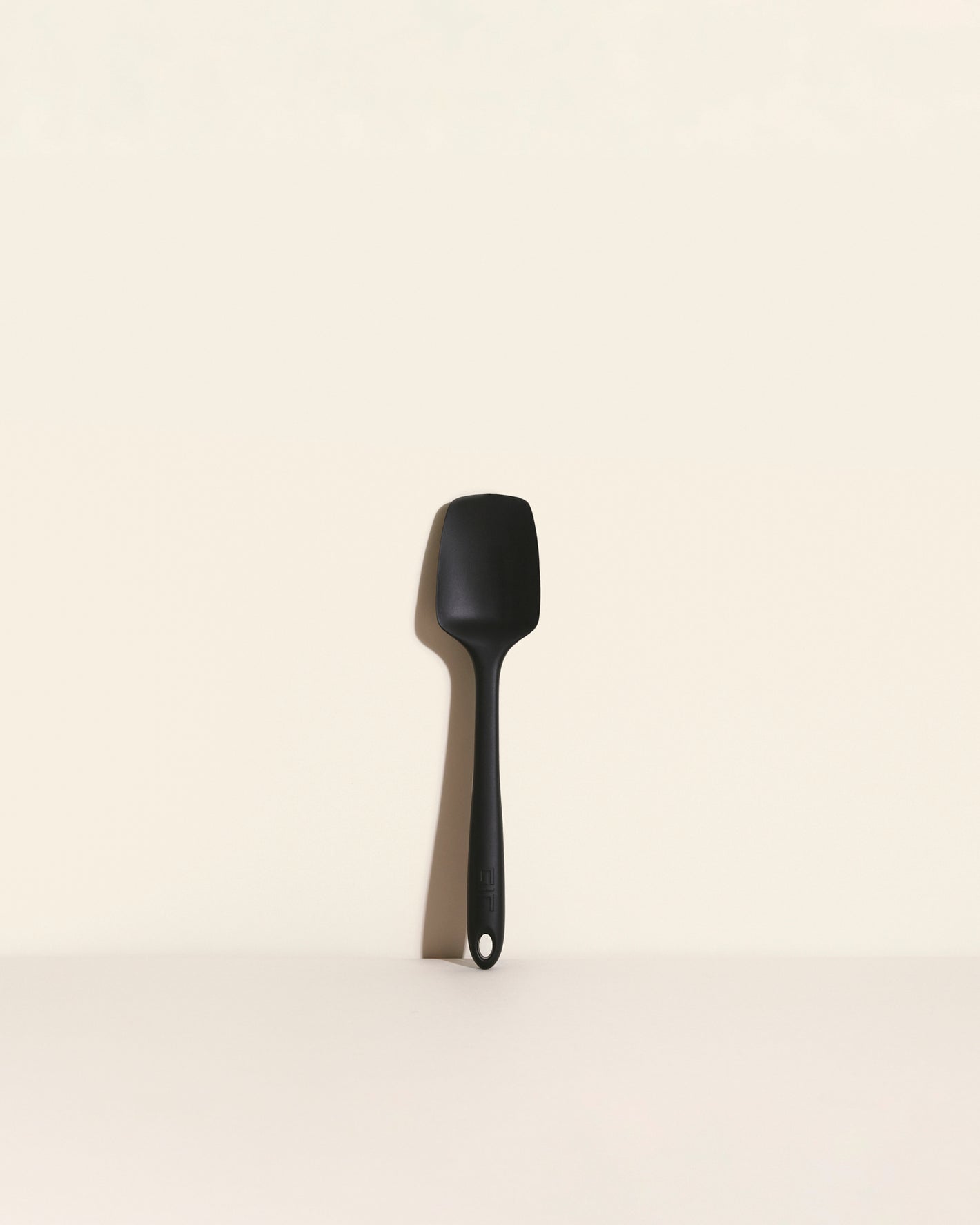 The Black Ultimate Spoonula on a cream background.