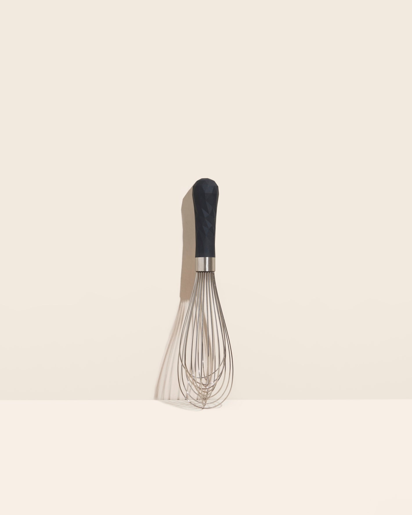 The Black Ultimate Whisk on a cream background.