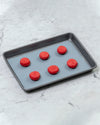 How To Use a Silicone Baking Mat with red macarons baking on a tray.