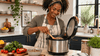 An elderly black woman cooking a quinoa in rice cooker.
