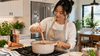 An Asian mother cooking using a pot and a spurtle.