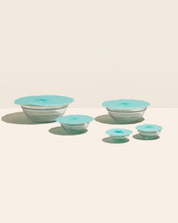 The Sea Foam  5 Piece Suction Lid set covering glass bowls on a cream background. 