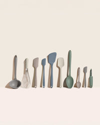 Set of kitchen utensils including ladles, spatulas, and whisks on a beige background