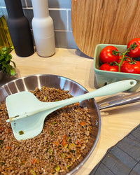 The Mint Quad Chopper on a pan of minced meat placed in a wooden surface. 