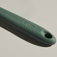 The GIR Sage Green Mini Spatula handle on a grey background.