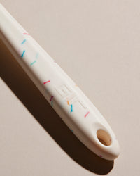 Close up of the Spatula Handle in Sprinkle on a cream background. 
