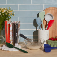 Different GIR Kitchen tools on a wooden kitchen counter with books and a vase on the left