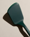 Close up of the Dark Green Ultimate Spatula on a cream background. 