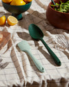 Close up of the GIR Emerald Ultimate Spoon and Mint Ultimate Spatula resting on a checkered table cloth 