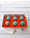 The Red 9 x 12 Baking mat on a baking tray with teal macaroons on it. 