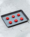 The Half Sheet Slate Baking Mat with Red Macaroons on it. 