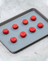 The Standard Quarter Slate Baking Mat with Red Macaroons on it. 