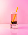 A Smoothie & Boba Straw inside a Boba Drink on a pink background 