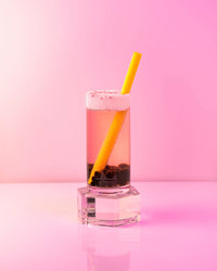 A Smoothie & Boba Straw inside a Boba Drink on a pink background 