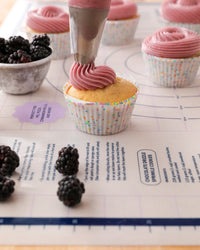 The GIR Confetti Cupcake Liners with cupcakes and icing on a GIR Pastry Mat. 