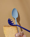 The Slate Mini Spoon on a cream background with the Spaghetti spoon in front of it. 