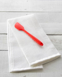 The Red Mini Spatula resting on a Onsen Waffle Hand Towel. 