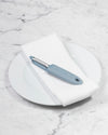  The I Handle Flat Peeler in Slate on a white towel and plate