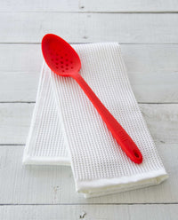 The Red Perforated Spoon resting on a Onsen Waffle Hand Towel. 