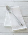The Studio Perforated Spoon on a white towel. 
