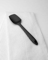 The Black Ultimate Spoonula resting on an Onsen Waffle Towel. 