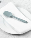 The GIR Slate Spoonula resting in a white Towel and Plate on a marble surface. 