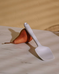 The GIR Studio Ultimate Spoonula resting on a pear on a marble surface. 