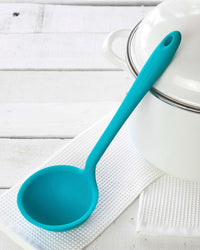 The Teal Ultimate Ladle on a white towel on a white background.  