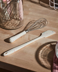 The Sprinkles Whisk next to the Sprinkles Spatula on a wooden surface.  