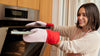 A woman wearing the GIR Oven Mits and opening the oven.