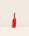 The I Handle Serrated Peeler in Red on a cream background. 