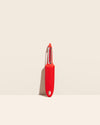 The I Handle Flat Peeler in Red on a cream background. 