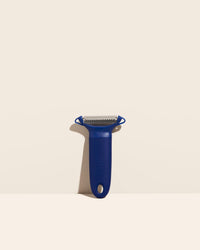  The Y Handle Julienne Peeler in Navy on a cream background. 