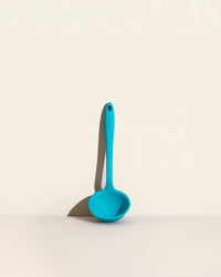 The Teal Ultimate Ladle on a cream background. 