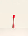 The Red Skinny Spatula on a cream background. 