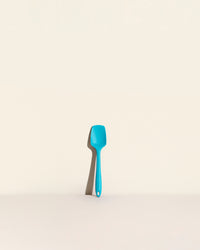 The Teal Mini Spoonula on a cream background. 