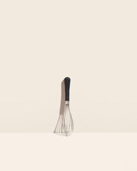 The Black Mini Whisk on a cream background. 