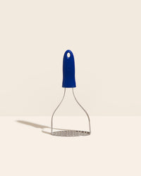 The GIR Perforated Masher in Navy on a cream background. 