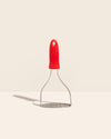 The GIR Perforated Masher in red on a cream background. 