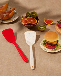 The GIR Ultimate Turner in Red and Sprinkle next to each other on a table with food and fruits around it.  