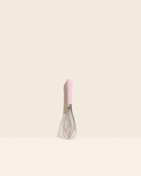 The Light Pink Mini Whisk on a cream background. 