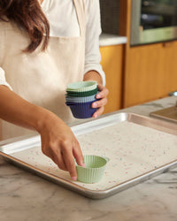 A lady placing the Frosty Mint Cupcake Liners on a baking tray. 