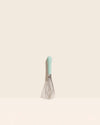 The Mint Mini Whisk on a cream background. 
