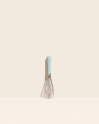 The Mint Mini Whisk on a cream background. 